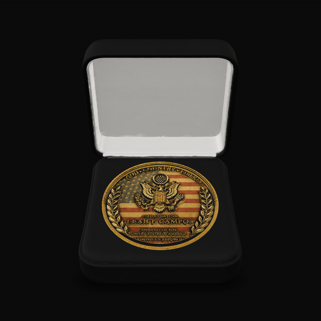 A round commemorative coin or medallion displayed inside an open black presentation box on a black background. 