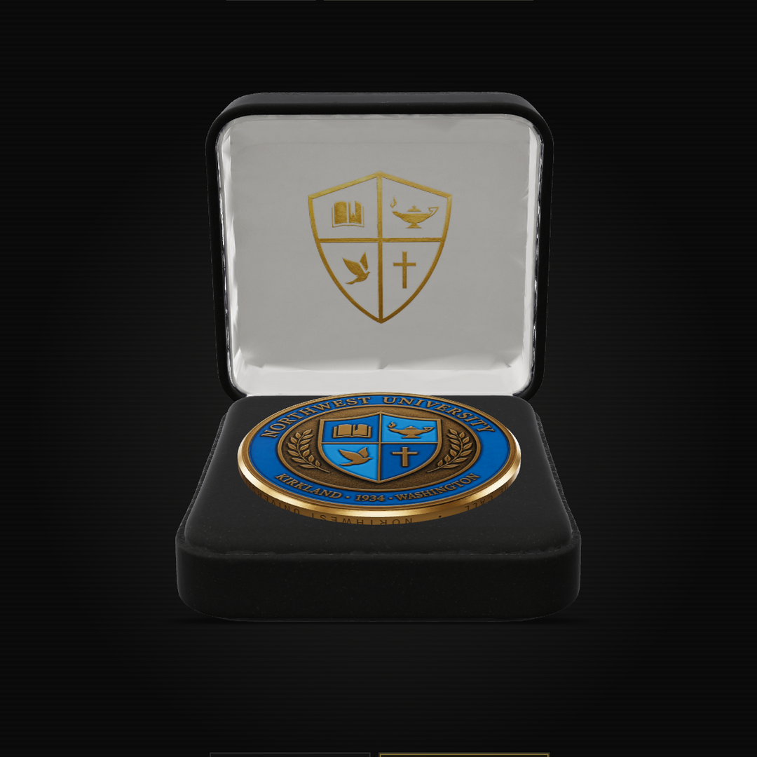 A round commemorative coin with blue and gold detailing, presented inside an open black velvet case with a white interior and a gold crest on the lid, set against a solid black background.