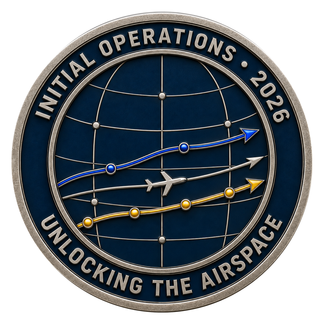 A circular commemorative coin or medallion with a dark blue globe design, silver-toned border and text reading 'INITIAL OPERATIONS • 2026' and 'UNLOCKING THE AIRSPACE,' plus blue, gray, and gold flight-path graphics and a small airplane icon.